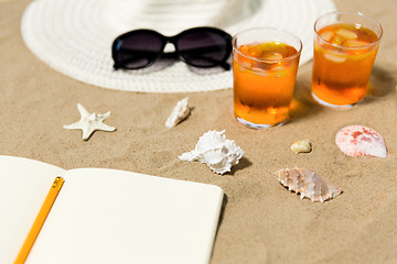 Image showing notebook, cocktails, hat and shades on beach sand