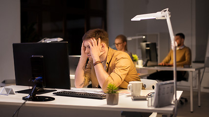 Image showing stressed man at computer monitor at night office