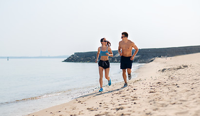 Image showing couple in sports clothes running along on beach