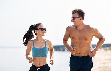 Image showing couple in sports clothes running along on beach