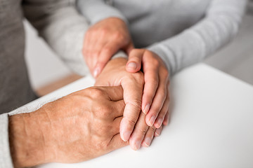 Image showing close up of young woman holding senior man hands