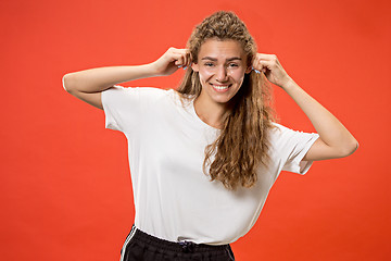 Image showing The happy woman standing and smiling against red background.