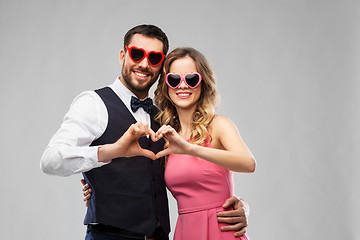 Image showing couple in sunglasses making hand heart gesture