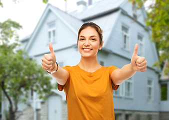 Image showing teenage girl showing thumbs up over house