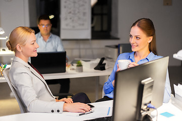 Image showing businesswomen drinking coffee at night office