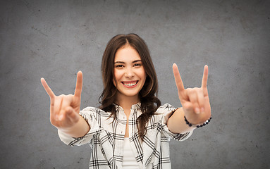 Image showing teenage girl showing rock sign over concrete wall