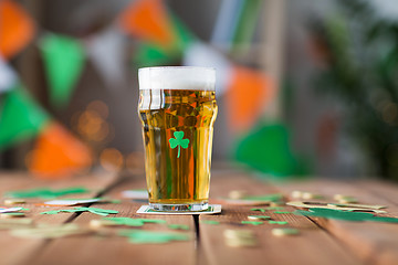 Image showing glass of beer with shamrock and coins on table