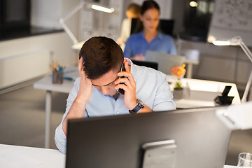 Image showing stressed man calling on smartphone at night office