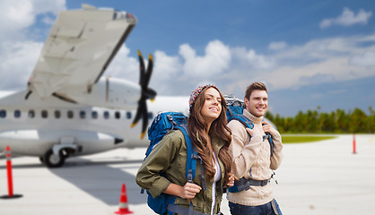 Image showing couple of tourists with backpacks over plane