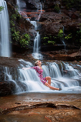 Image showing Exhilaration in mountain waterfall, female sitting in flowing ca