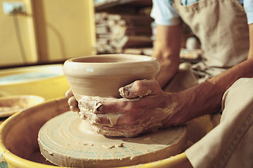 Image showing Creating a jar or vase of white clay close-up. Master crock. Man hands making clay jug macro.