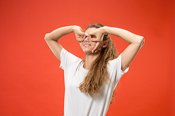 Image showing The happy woman standing and smiling against red background.