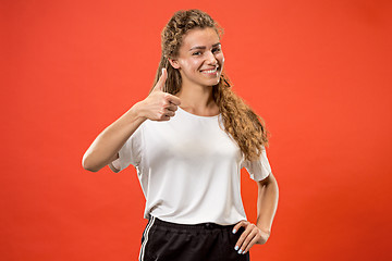 Image showing The happy business woman standing and smiling against red background.