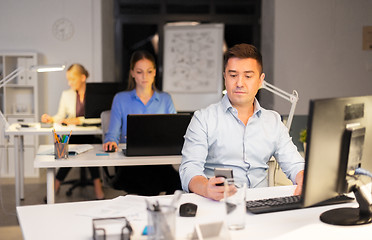 Image showing man with smartphone working at night office