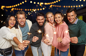 Image showing happy friends with sparklers at rooftop party