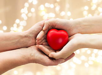 Image showing senior and young man hands holding red heart