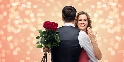 Image showing woman with engagement ring and roses hugging man