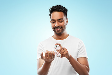 Image showing happy indian man with perfume over blue background