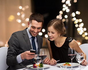 Image showing couple with smartphone eating at restaurant