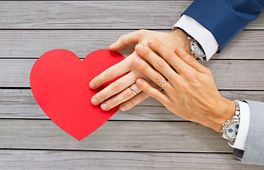 Image showing close up of male gay couple hands with red heart