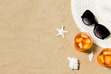 Image showing cocktails, sun hat and sunglasses on beach sand