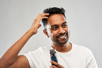 Image showing smiling indian man with trimmer touching his hair