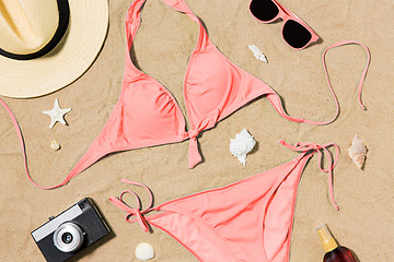 Image showing bikini, hat, camera and sunglasses on beach sand