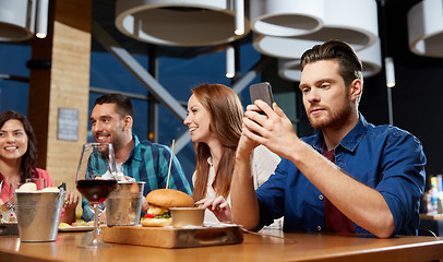 Image showing man messaging on smartphone at restaurant