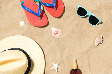 Image showing straw hat, flip flops and sunglasses on beach sand