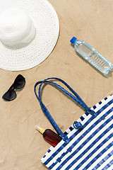 Image showing beach bag, sunscreen, sunglasses and hat on sand