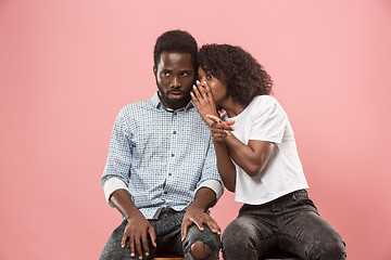 Image showing The young woman whispering a secret behind her hand to afro man