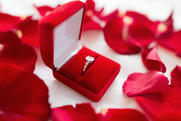 Image showing diamond ring in red velvet gift box on bed sheet