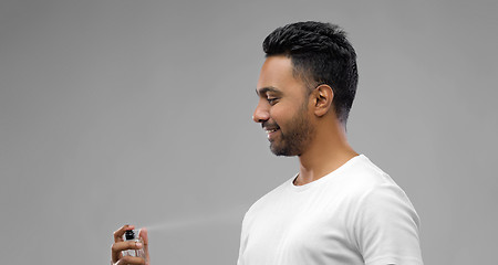 Image showing happy indian man with perfume over grey background