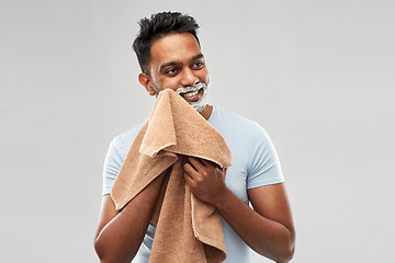 Image showing man removing shaving foam from face by towel