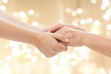 Image showing close up of senior and young man holding hands