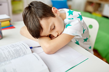 Image showing tired student boy sleeping on table at home