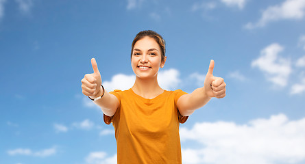 Image showing teenage girl in t-shirt showing thumbs up over sky