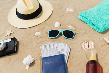 Image showing money in passport, shades and hat on beach sand