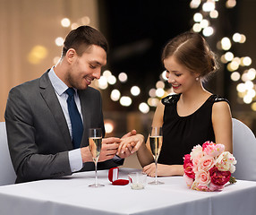 Image showing man giving woman engagement ring at restaurant