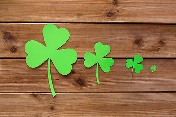 Image showing green paper shamrocks on wooden background