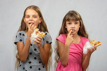 Image showing Two girls are funny eating bread, pushing food into your mouth with your fingers