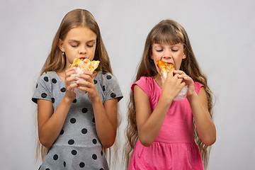 Image showing Two hungry girls eat bread