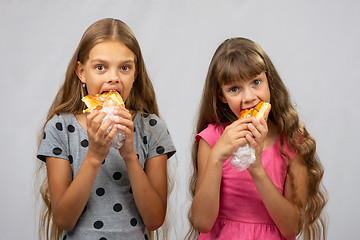 Image showing Two hungry girls eat bread, and look at the frame