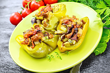 Image showing Pepper stuffed with vegetables in green plate on dark wooden board