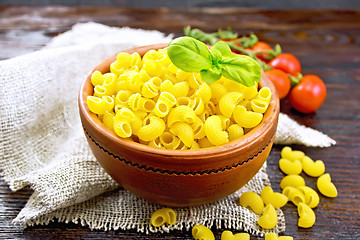 Image showing Elbow macaroni in bowl with tomatoes and basil on board