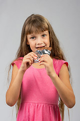 Image showing Eight-year-old girl eats chocolate bar