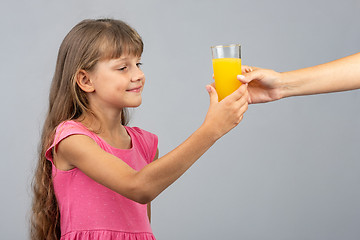 Image showing The girl takes from her hand a glass of orange juice