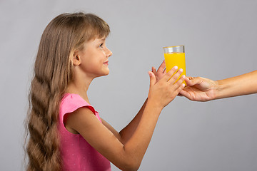 Image showing The hand holds out a glass of orange juice