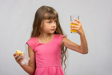 Image showing The girl intently looks at a glass of juice