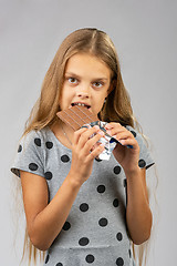 Image showing A ten-year-old girl eats a chocolate bar